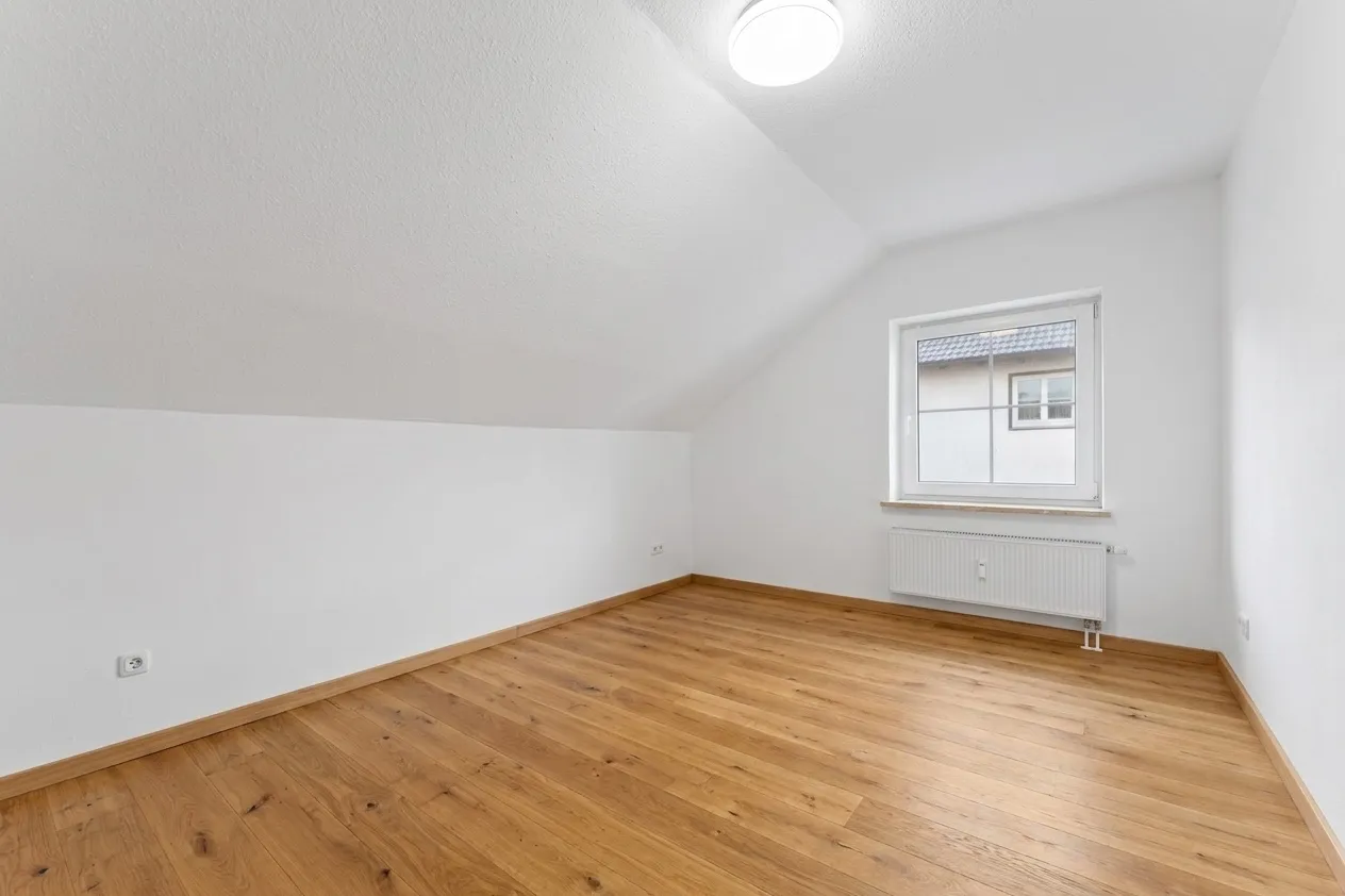 Zimmer mit Dachschräge und Fenster, renoviert und leer