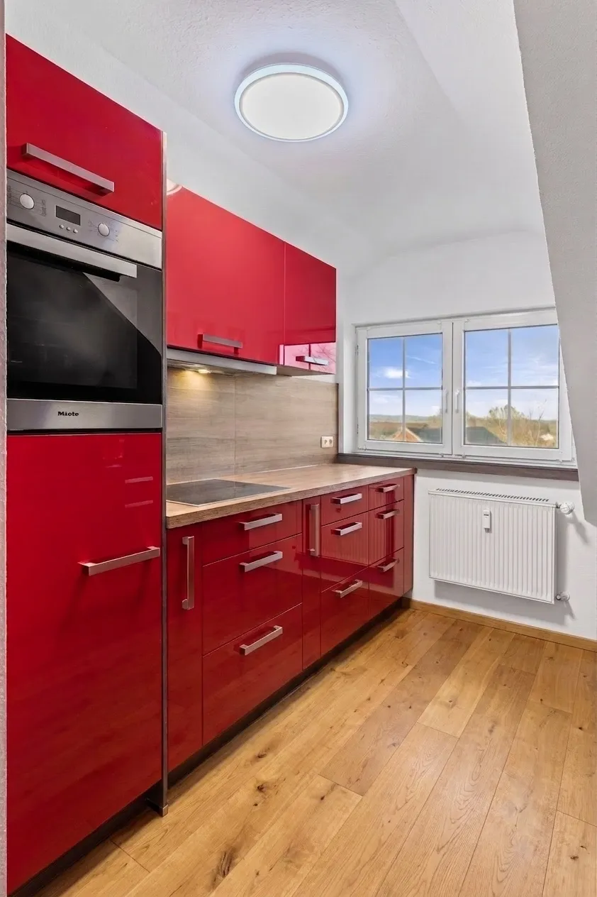 Küchenzeile mit Backofen, Kochfeld und Fenster