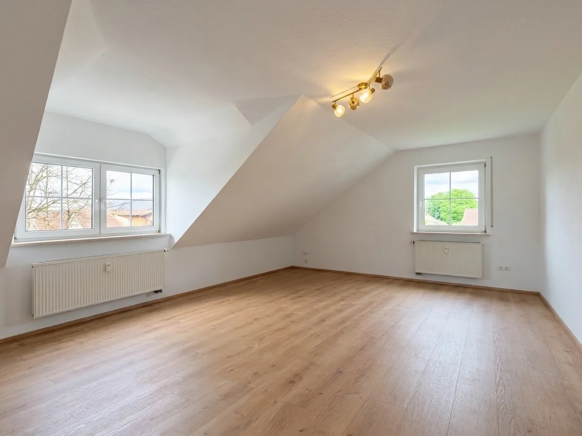 Wohnzimmer mit zwei Fenstern und Dachschräge, renoviert und leer