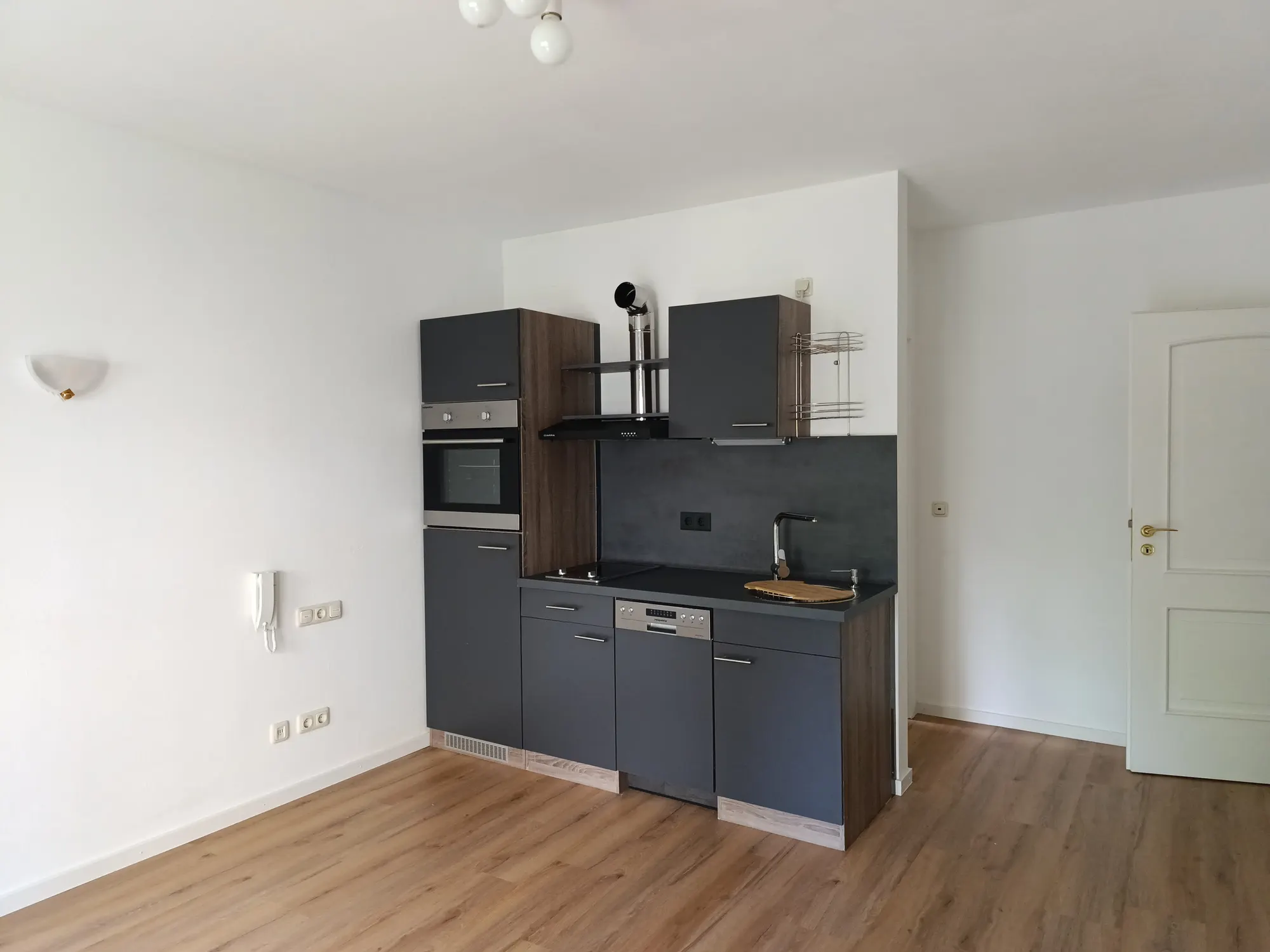 Heller Wohnraum mit Pantryküche und Boden in Holzoptik