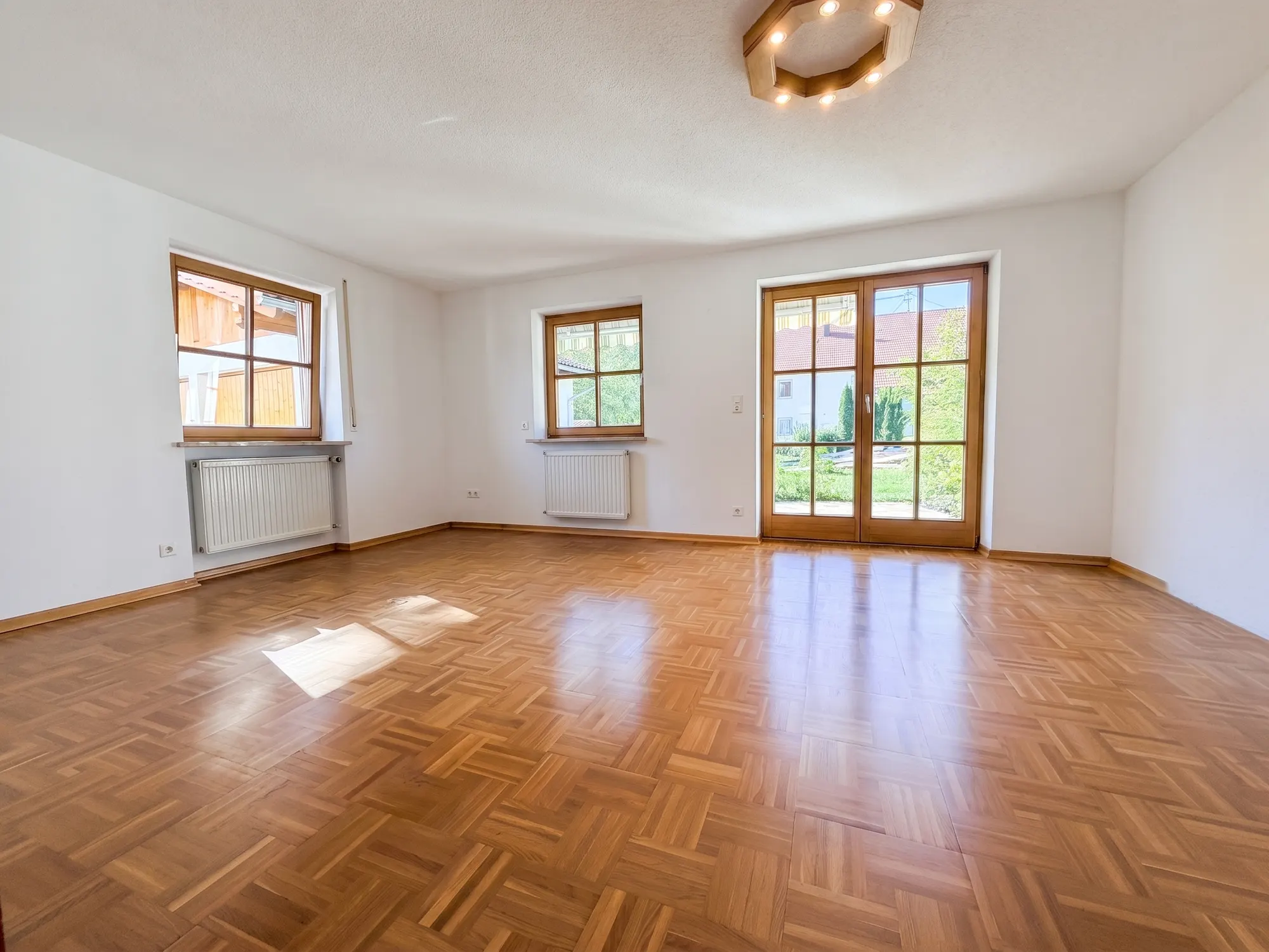 Wohnzimmer mit Mosaikparkett und Tür zur Terrasse