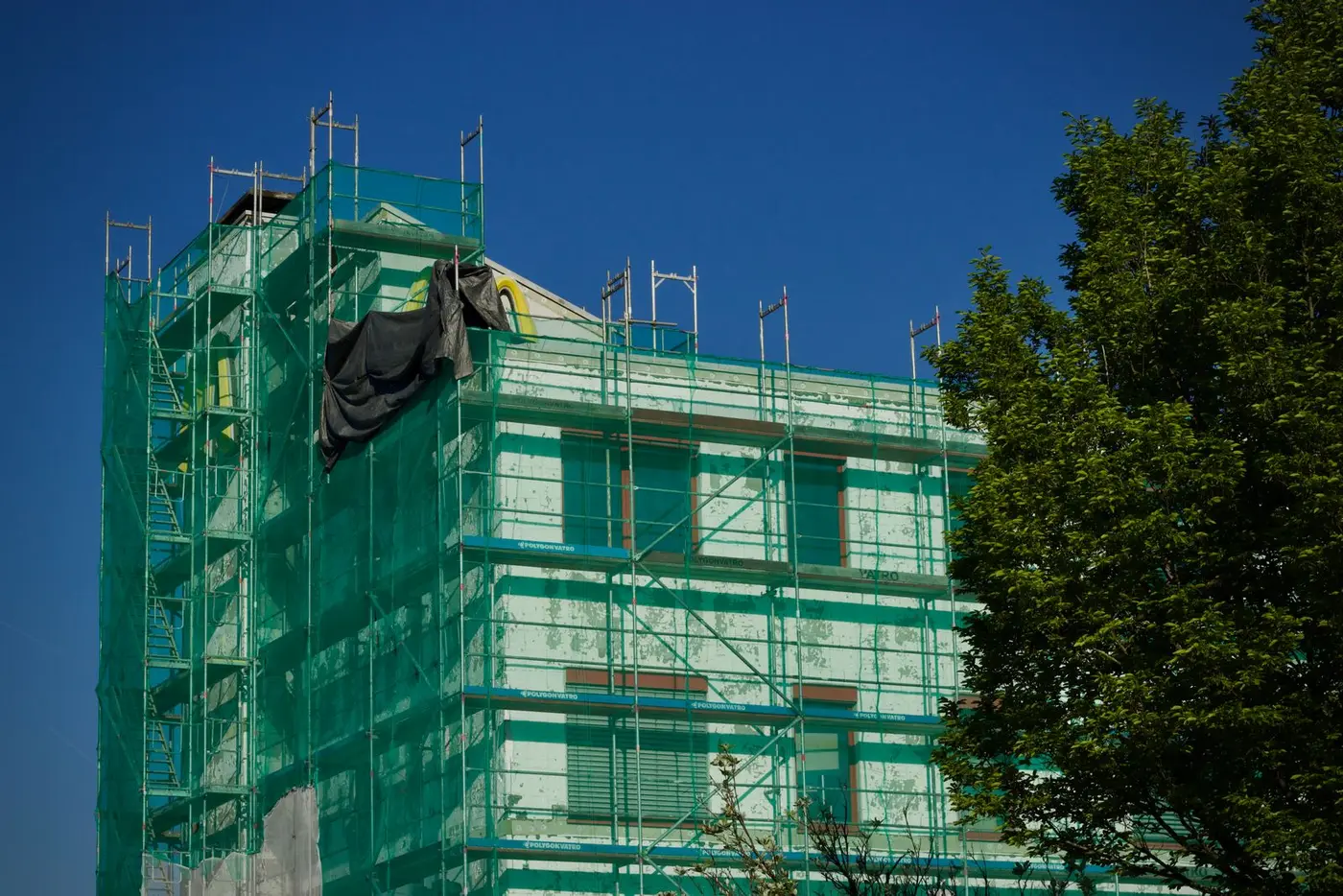 Eingerüstetes Mehrfamilienhaus mit Dämmplatten während einer energetischen Sanierung