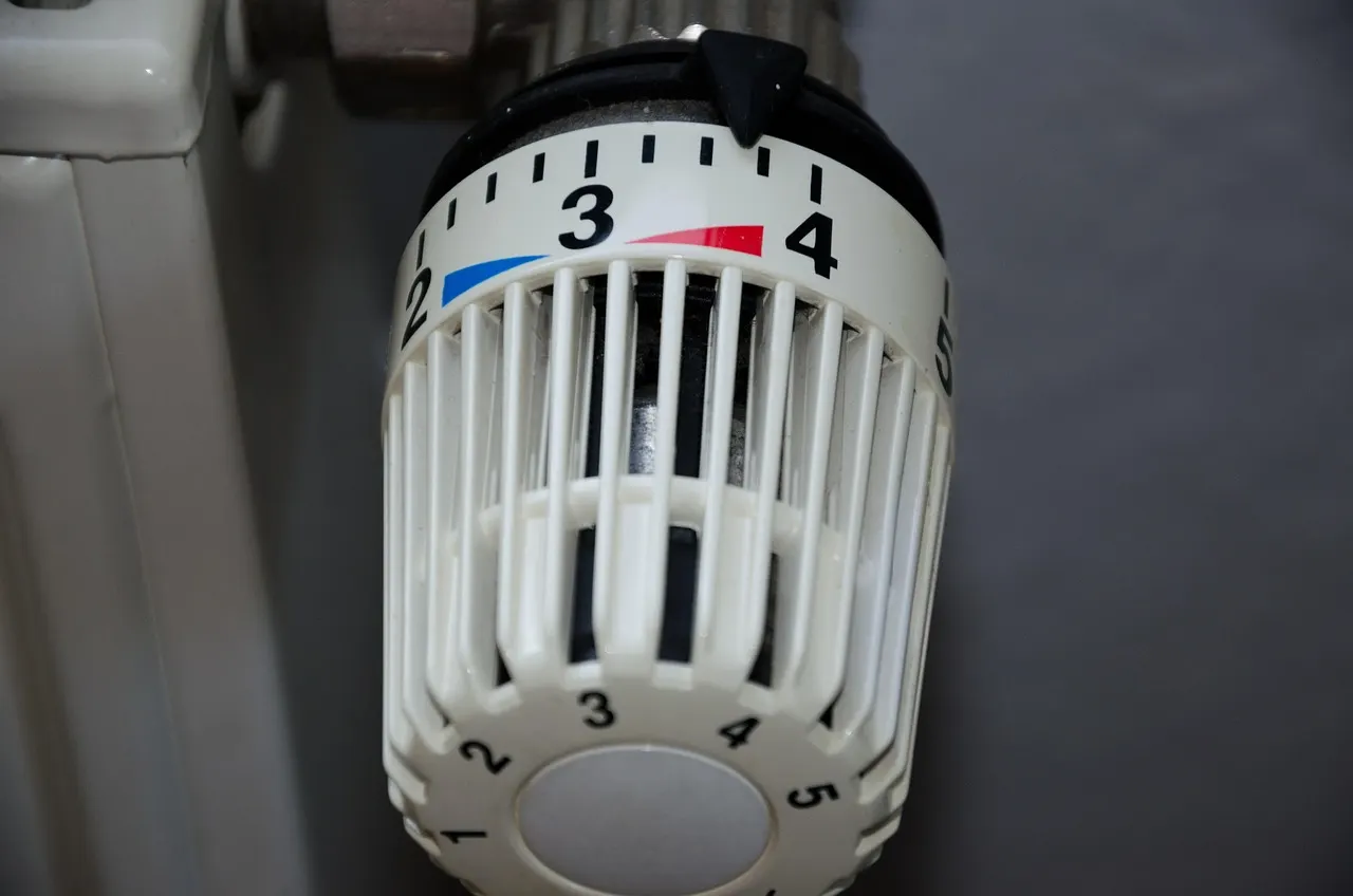 Thermostatkopf an einem weißen Heizkörper, Skala zwischen den Stufen 3 und 4