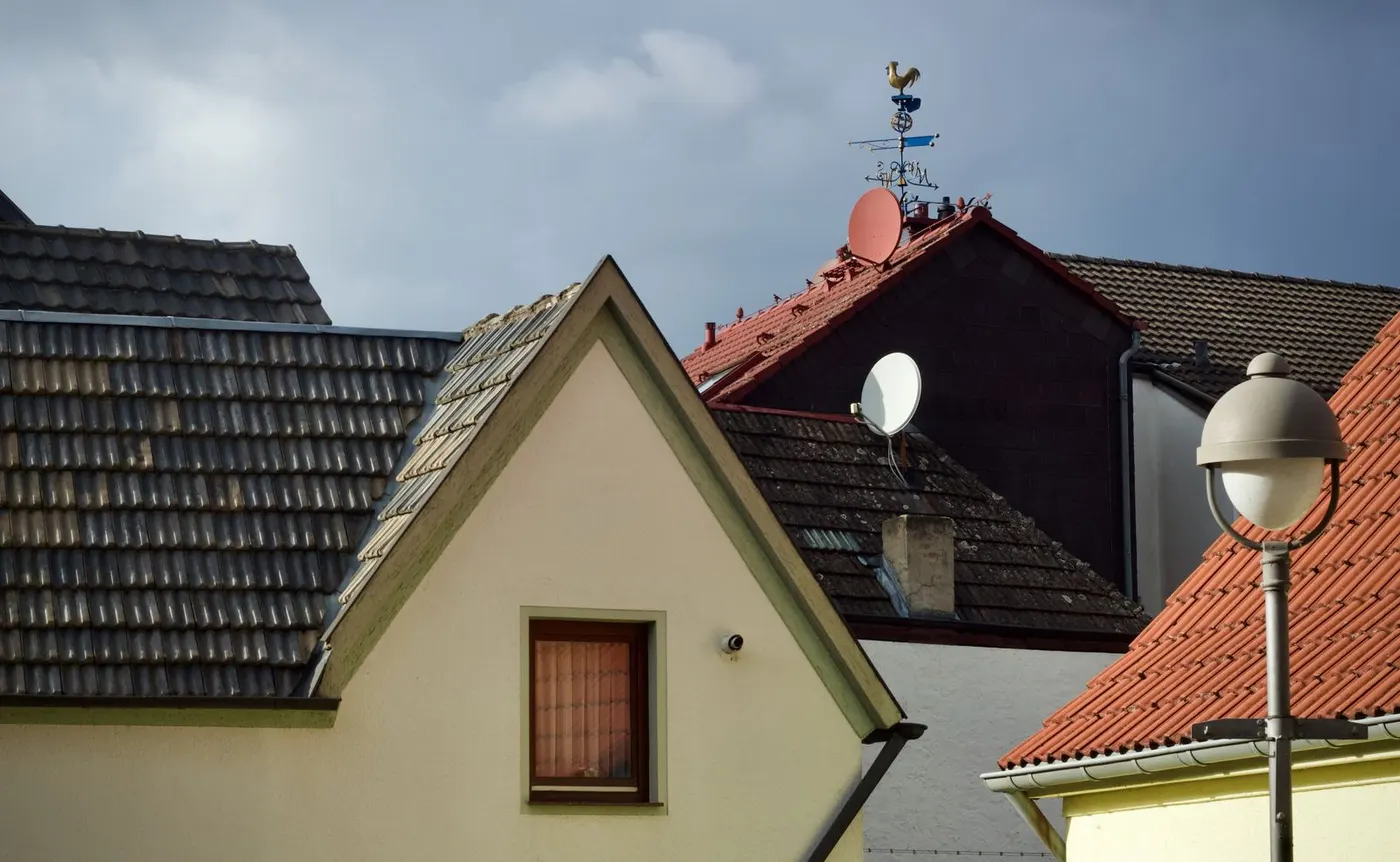 Satellitenschüsseln auf den Ziegeldächern mehrerer Wohnhäuser